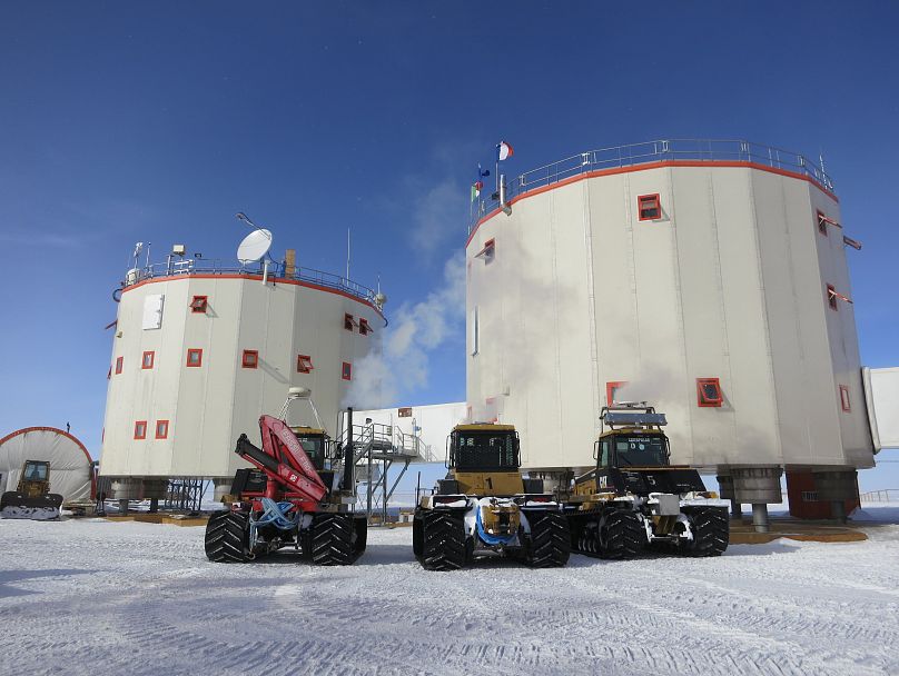 Three rugged vehicles parked in front of Concordia research base in Antarctica. 