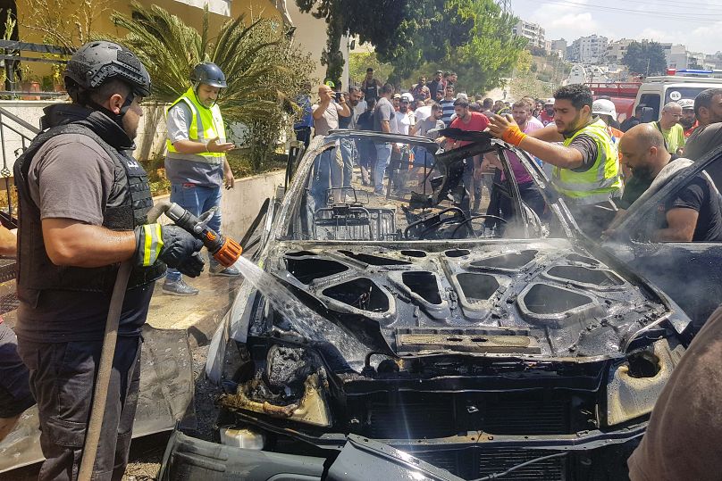 Des employés de la défense civile inspectent les restes d'une voiture touchée par une frappe israélienne dans la ville portuaire de Sidon, au Liban, le lundi 26 août 2024.