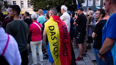 A man covering with a German national flag with the slogan "We are the people" listens to Bjoern Hoecke, top candidate of AfD , during an election campaign rally of the party.