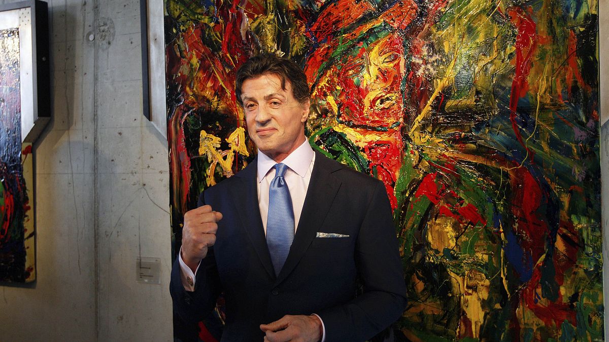 US Actor Sylvester Stallone, poses in front of one of his works during a press conference ahead of the exhibition "Sylvester Stallone. 35 Years of Painting" in 2011.