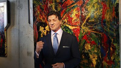 US Actor Sylvester Stallone, poses in front of one of his works during a press conference ahead of the exhibition "Sylvester Stallone. 35 Years of Painting" in 2011.