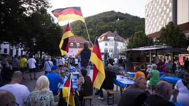 People wave German national flags as they listen to Bjoern Hoecke, top candidate of the far-right Alternative for Germany party, or AfD, during an election campaign rally.