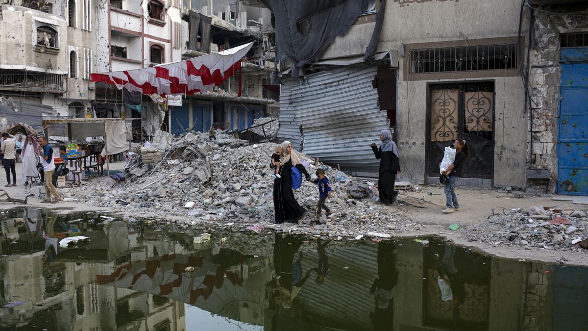 Des Palestiniens déplacés par l'offensive aérienne et terrestre israélienne sur la bande de Gaza marchent le long d'une traînée sombre d'eaux usées à Khan Younis.