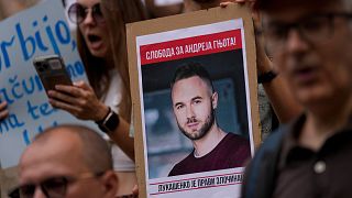 A man holds a banner of Andrei Hniot during a protest against his extradition outside the Serbian appeals court in Belgrade on Tuesday, August 27, 2024.