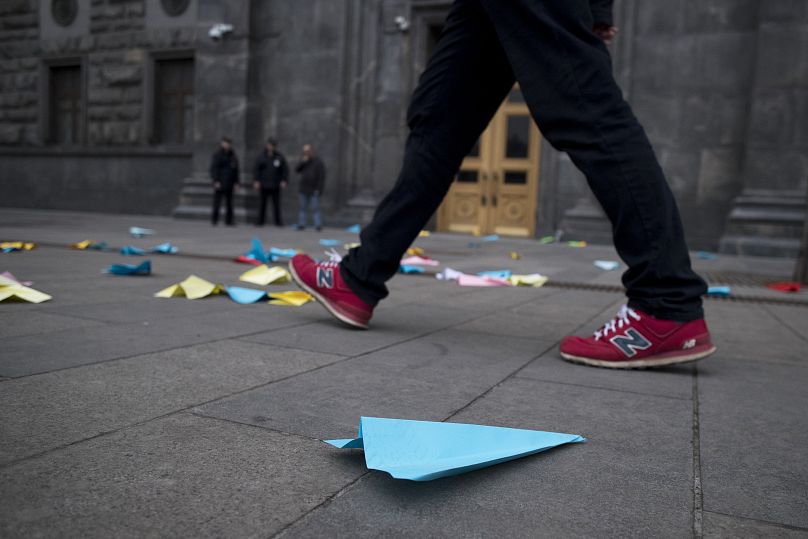 La gente pasa junto a aviones de papel arrojados por manifestantes frente al edificio del Servicio Federal de Seguridad en la Plaza Lubyanskaya en Moscú, Rusia.