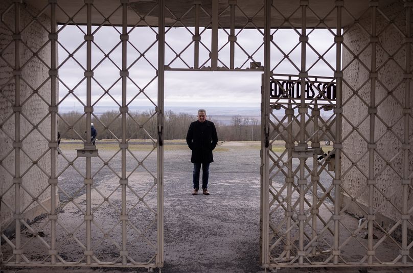 The head of the Buchenwald Memorial, Jens-Christian Wagner, poses for a photo behind the main gate of the former Nazi concentration camp in Weimar, Germany, Wednesday, Jan. 31