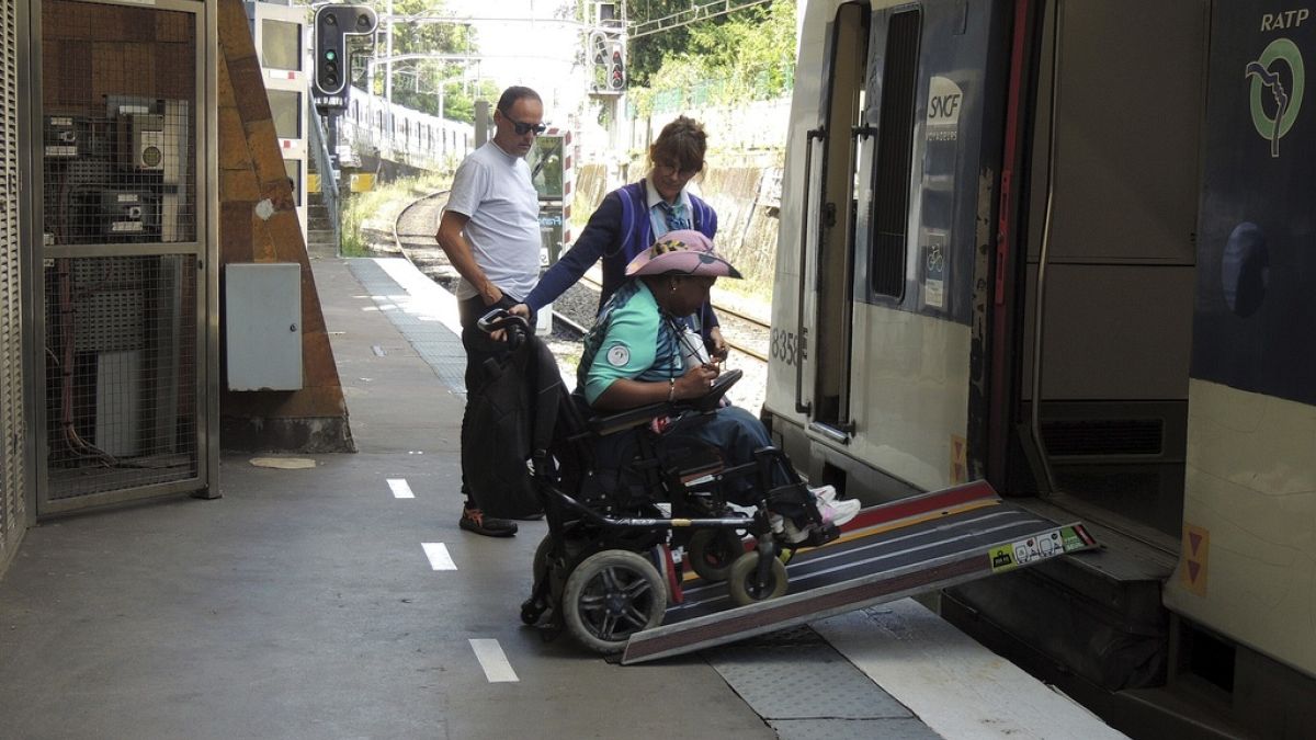 Egy mozgássérültet segítenek felszállni a RER egyik járatára - képünk illusztráció