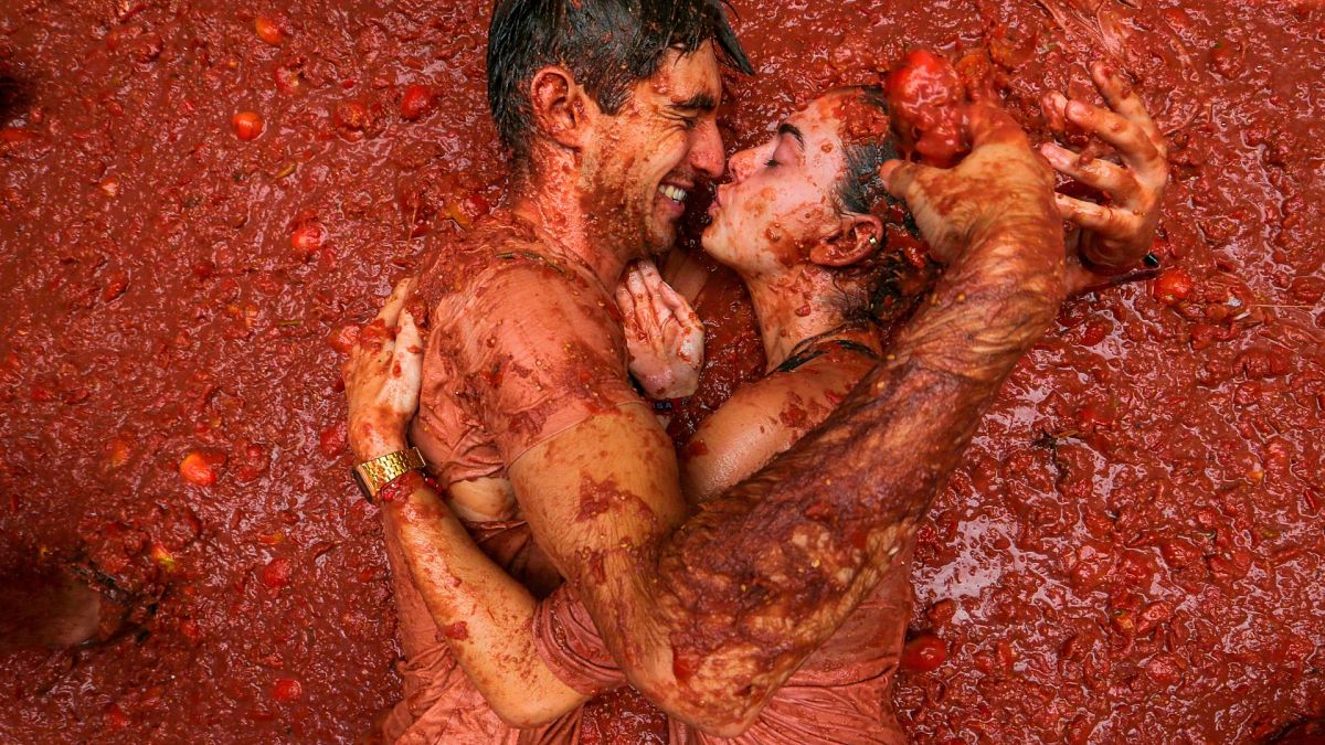 Revelers lie in a pool of squashed tomatoes during the annual "Tomatina" tomato fight fiesta, in the village of Bunol near Valencia, Spain, 28 August 2024.