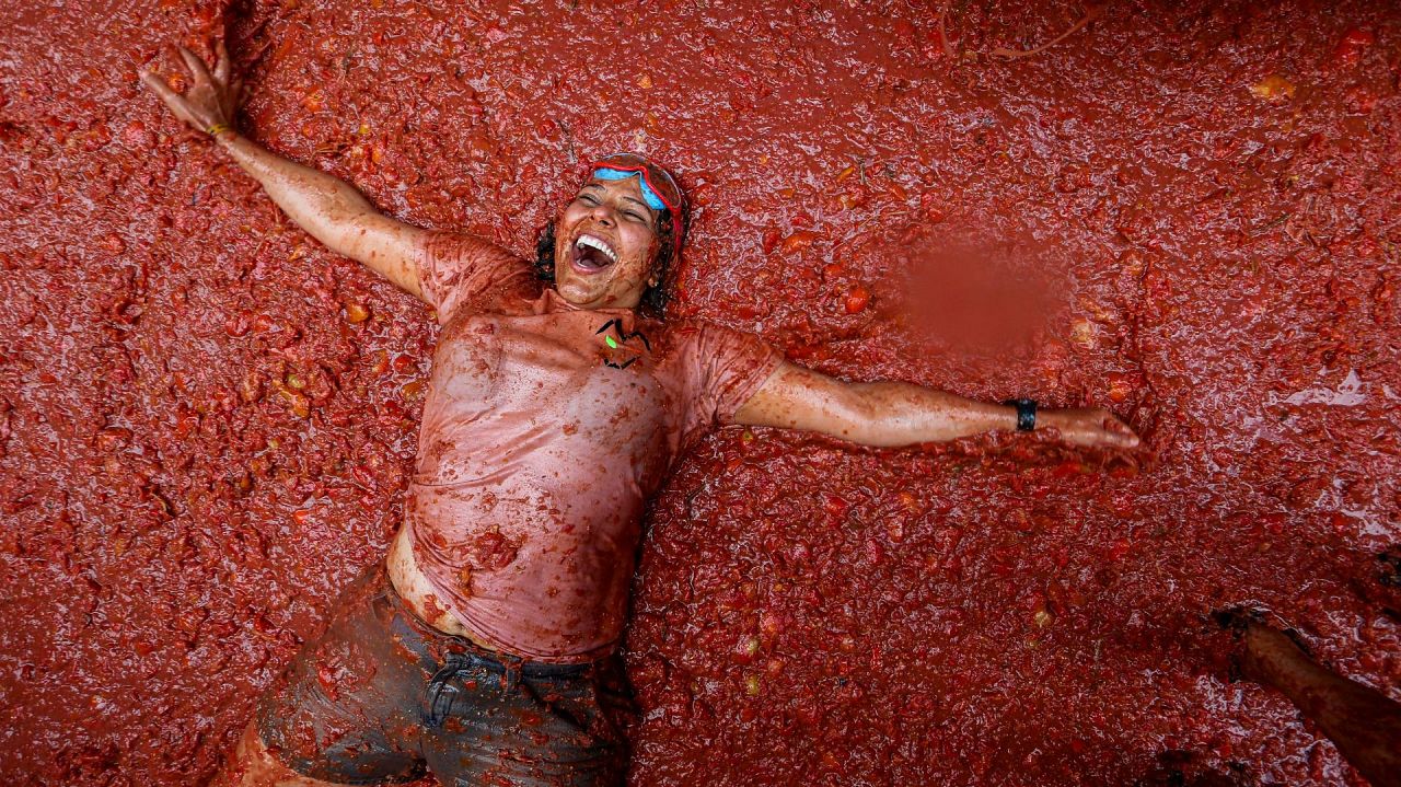 A reveller lies in a pool of squashed tomatoes during the annual "Tomatina"