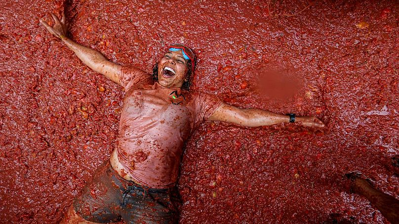 Una participante yace en un charco de tomates aplastados durante la Tomatina anual