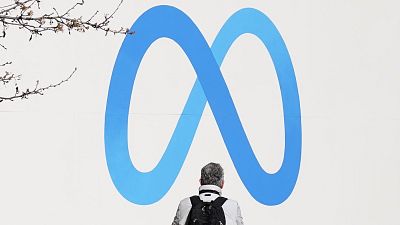 FILE - A person stands in front of a Meta sign outside of the company's headquarters in Menlo Park, California, March 7, 2023.