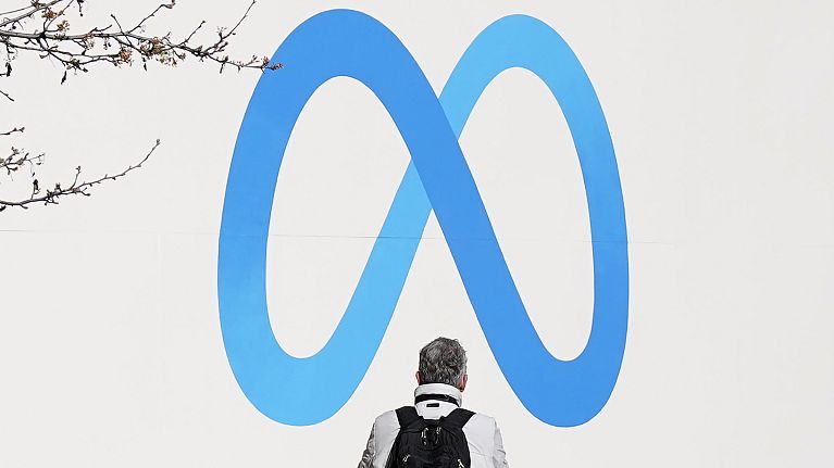 FILE - A person stands in front of a Meta sign outside of the company's headquarters in Menlo Park, California, March 7, 2023.