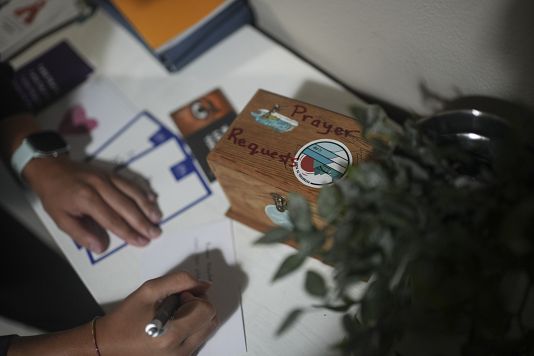 A Surf Church member writes next to a prayer petition box at the church in the suburbs of Porto, Portugal on Aug. 18, 2024. 