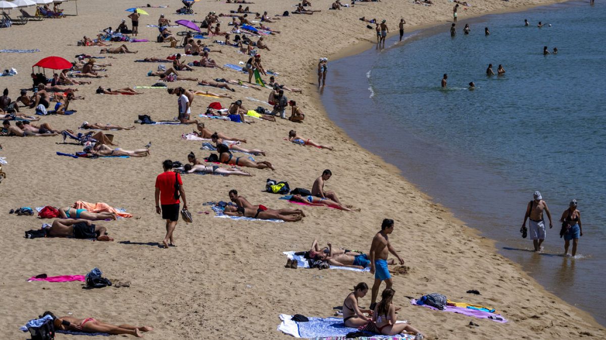 أشخاص يأخذون حمام شمس على الشاطئ في برشلونة، إسبانيا، الثلاثاء 8 يونيو 2021 (AP Photo/Emilio Morenatti)