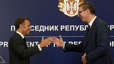 French President Emmanuel Macron clasps hands with Serbian President Aleksandar Vučić after a press conference in Belgrade, August 29, 2024