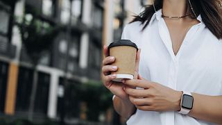 A girl holding a cup of coffee to go