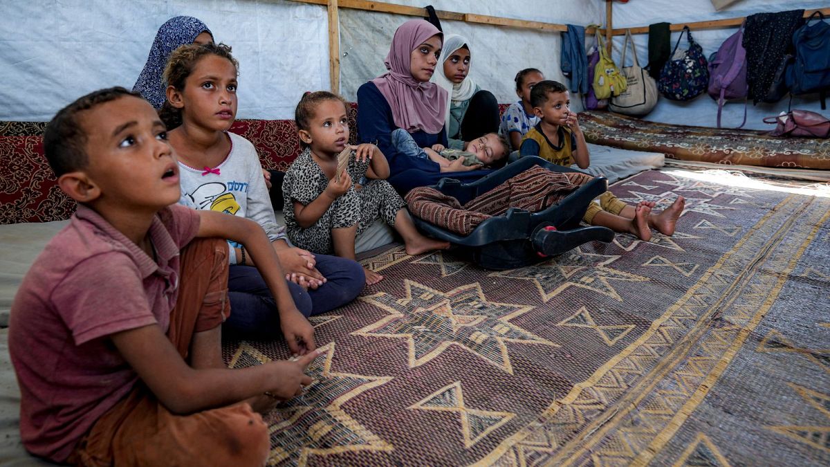 Abdel-Rahman Abu El-Jedian, 11 mois, atteint de poliomyélite, est porté par sa mère dans un camp de tentes improvisé à Deir al-Balah.