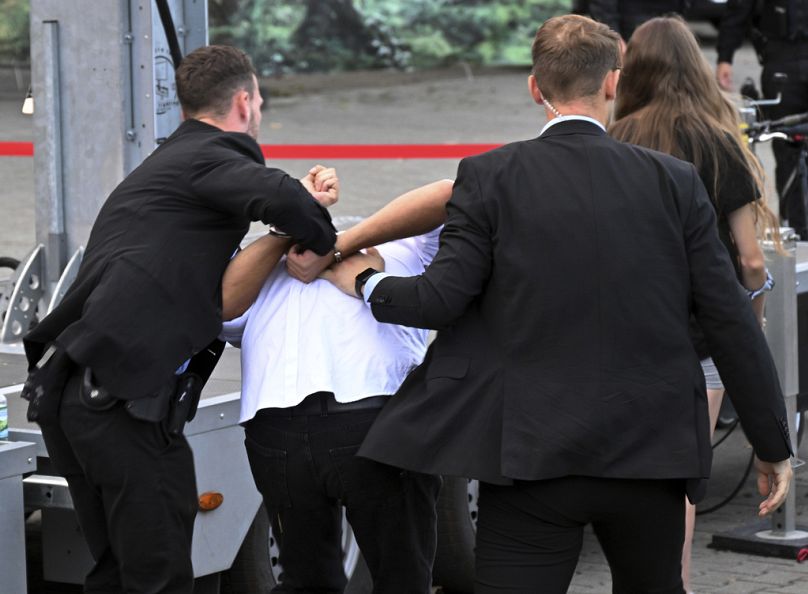 Bodyguards take away a man who allegedly carried out an attack with red paint at an election campaign event organized by the Sahra Wagenknecht Alliance (BSW)