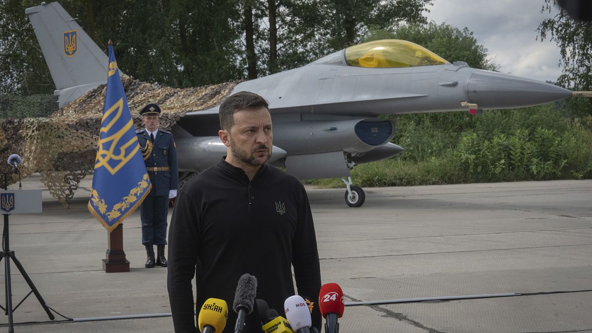 Ukraine's President Volodymyr Zelenskyy answers press questions standing in front of an F-16 fighter jet in an undisclosed location in Ukraine, August 4, 2024