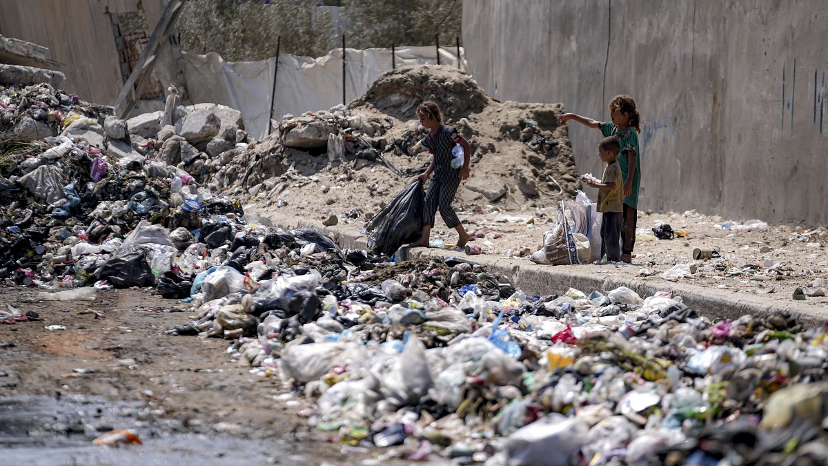 أطفال نازحون يفرزون القمامة في أحد شوارع دير البلح وسط قطاع غزة، الثلاثاء، 27 أغسطس/آب 2024