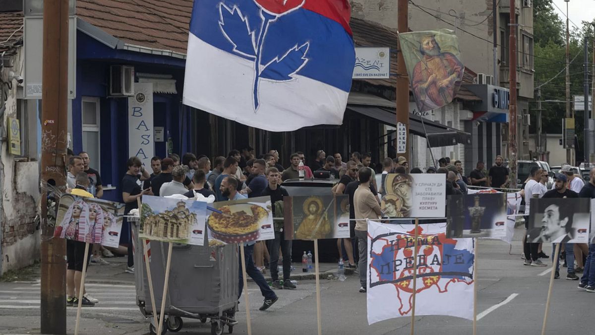 Bir kişi, Kosova'nın Mitrovica kentindeki köprüdeki barikatın bir parçası olan yanmış bir kamyonun fotoğraflarını çekiyor, 29 Aralık 2022.