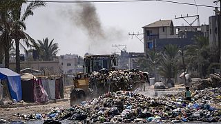 Um bulldozer limpa plástico e outros resíduos numa rua em Deir al-Balah, no centro da Faixa de Gaza