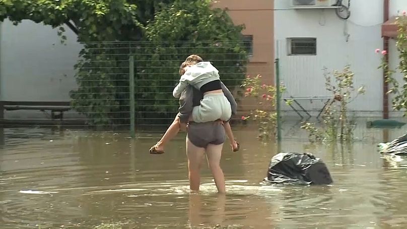 Una mujer lleva a una niña sobre la calle inundada en Constanza, 31 agosto 2024