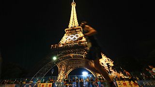 Spectators stand at the base of the Eiffel Tower as they watch runners participate in the Pour Tous marathon, at the 2024 Summer Olympics, in Paris, Saturday, Aug. 10, 2024. 