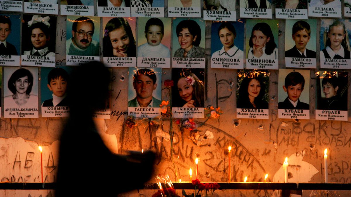 Una donna davanti al muro con i ritratti delle vittime della scuola di Beslan a un anno dalla strage, 2 settembre 2005