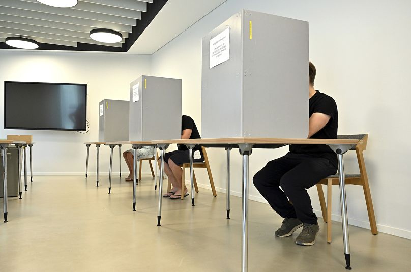 Eleitores em cabinas de voto para as eleições estaduais na Turíngia, numa assembleia de voto em Erfurt, 1 de setembro de 2024