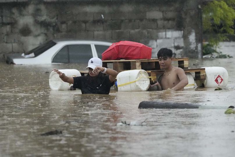 سكان يخوضون في عوامة مرتجلة وهم يعبرون شارعًا غمرته المياه بسبب الأمطار الغزيرة الناجمة عن العاصفة الاستوائية ياغي يوم الاثنين 2 سبتمبر/أيلول 2024 في كاينتا، مقاطعة ريزال، الف