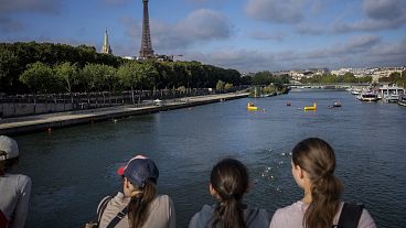 Spectators watch as Paralympic athletes compete in a swimming race along the Seine River during a Triathlon competition at the 2024 Paralympics