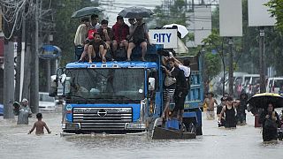 Des personnes sont montées sur un camion pour éviter les inondations causées par les fortes pluies de la tempête tropicale Yagi, appelée localement Enteng, lundi 2 septembre