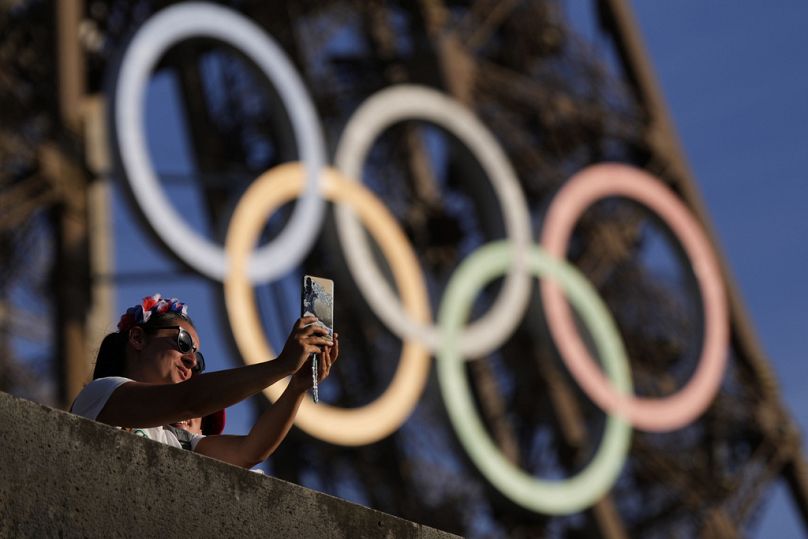 A person takes a selfie with the Olympic rings on the Eiffel Tower during the 2024 Summer Olympics, Tuesday, Aug. 6, 2024, in Paris, France.