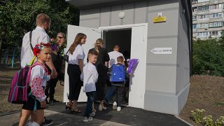 Schoolchildren and their parents enter an underground school on the first day at school in Kharkiv, Ukraine, Monday, Sept. 2, 2024. 