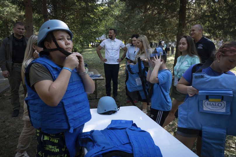 Çocukların Sesi Vakfı'nın savaştan etkilenen çocuklara yönelik düzenlediği rehabilitasyon kampında çocuklar, mayın güvenliği eğitimi sırasında kask ve yelek giyiyor.