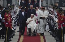 Papa Franjo u invalidskim kolicima drži kapu po dolasku tijekom službene ceremonije dočeka u međunarodnoj zračnoj luci Soekarno-Hatta.