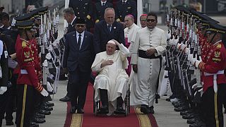 Pope Francis on his wheelchair, holds his cap upon arrival during an official welcoming ceremony at Soekarno-Hatta International Airport.