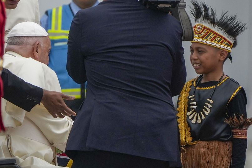 Papa Francesco viene accolto da bambini in abiti tradizionali subito dopo l'atterraggio all'aeroporto internazionale di Giacarta Soekarno Hatta