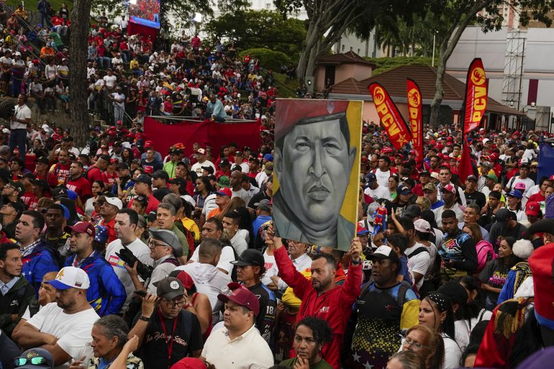 Membros do governo seguram um cartaz do falecido antigo Presidente Hugo Chávez à porta do palácio presidencial durante uma manifestação de apoio à reeleição de Maduro