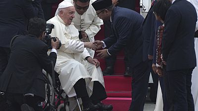 Pope Francis, left, is greeted by Indonesian Minister of Religious Affairs Yaqut Cholil Qoumas upon his arrival at Soekarno-Hatta International Airport in Tangerang, Indonesia