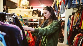 Uma mulher compra roupa em segunda mão numa loja em Londres.