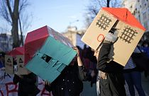 Two young women wear cardboard houses over their heads during a demonstration protesting Portugal's housing crisis, in Lisbon, Jan. 27, 2024.