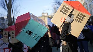 Manifestantes llevan casas de cartón sobre sus cabezas durante una protesta contra la crisis de la vivienda en Portugal, en Lisboa, el sábado 27 de enero de 2024.