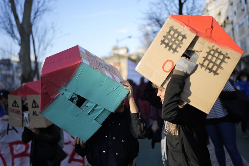 Two young women wear cardboard houses over their heads during a demonstration protesting Portugal's housing crisis, in Lisbon, January 2024