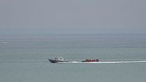 A boat thought to be with migrants is escorted by a vessel from the French Gendarmerie Nationale off the Wimereux beach, France