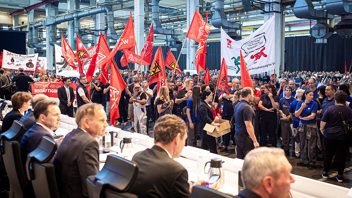 Çalışanlar Wolfsburg'daki VW fabrikasının bir salonunda iş toplantısının başlamasından önce protesto gösterisi yaptı