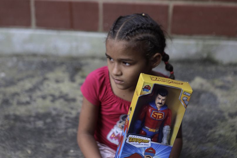 A child holds a "Super Bigote" action figure doll modeled after President Nicolas Maduro, a Christmas gifts delivered by government officials, Dec. 27, 2022.