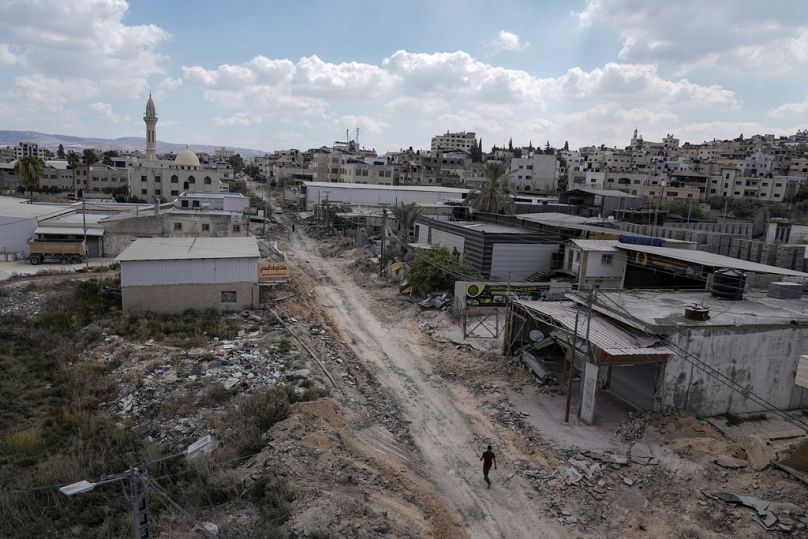 A man walks on a damaged road following an Israeli army raid in Jenin, West Bank, on Wednesday, Sept. 4, 2024.