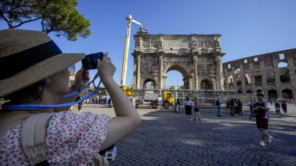 Bir turist, 4 Eylül 2024, Çarşamba günü Roma'da, Kolezyum yakınlarındaki M.S. 315 tarihli Konstantin Takı'nın fotoğraflarını çekiyor